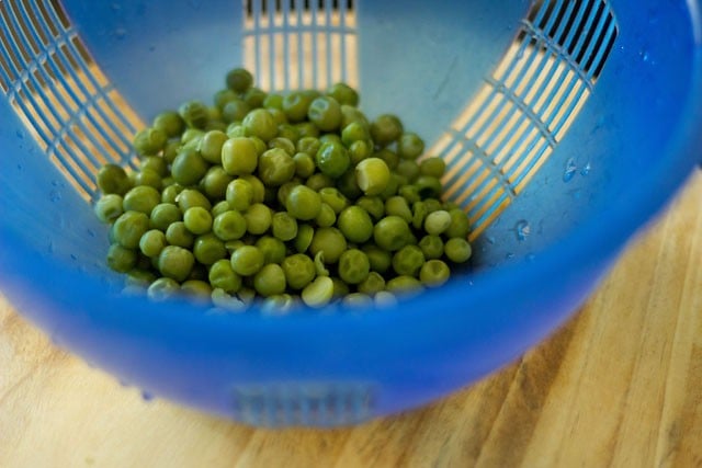 draining cooked green peas 