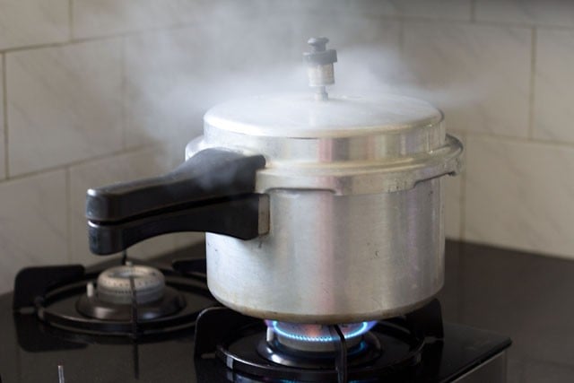 pressure cooker on a stove with steam coming out.