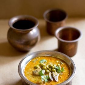 mushroom peas curry or batani curry served in a metallic small pan with copper glasses in the background