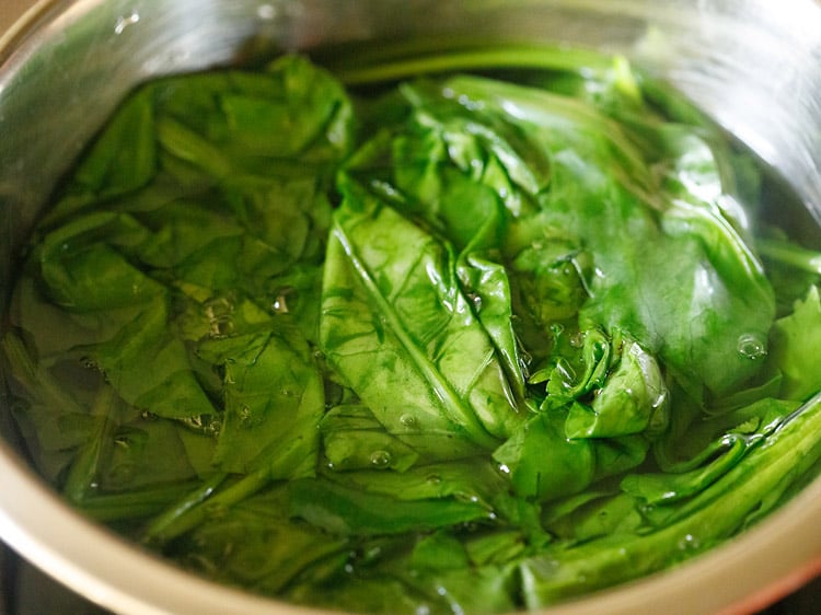 blanching spinach in hot water in a bowl