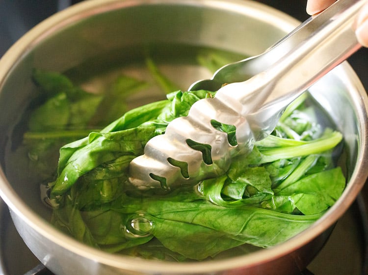 blanching spinach in hot water in a bowl