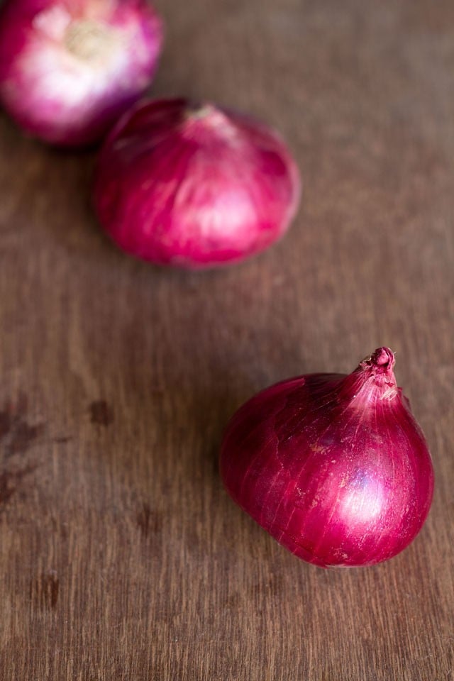 close up shot of red onions on a brown wooden board