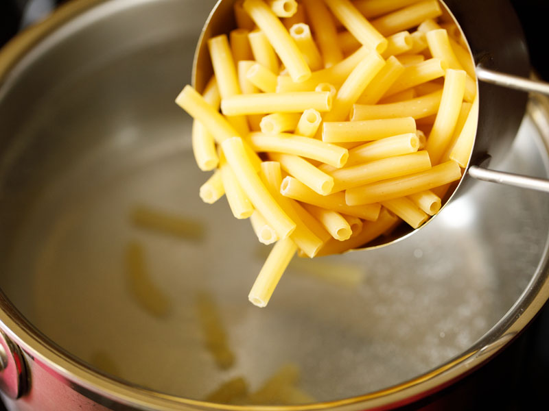 ziti pasta being added to hot water