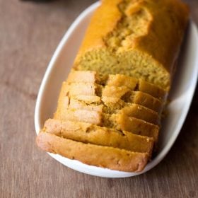 orange cake slices with the loaf on a white oblong tray on a wooden board