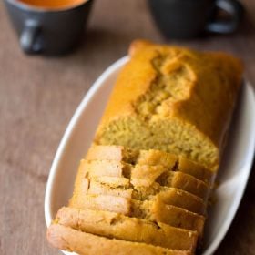 orange cake slices with the loaf on a white oblong tray on a wooden board