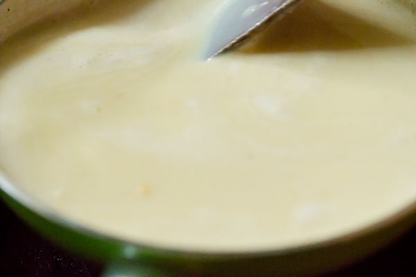 scraping the bottom of the pan with a spoon while making custard