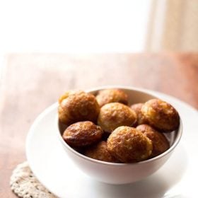 sweet paniyaram in a white bowl on a white plate.