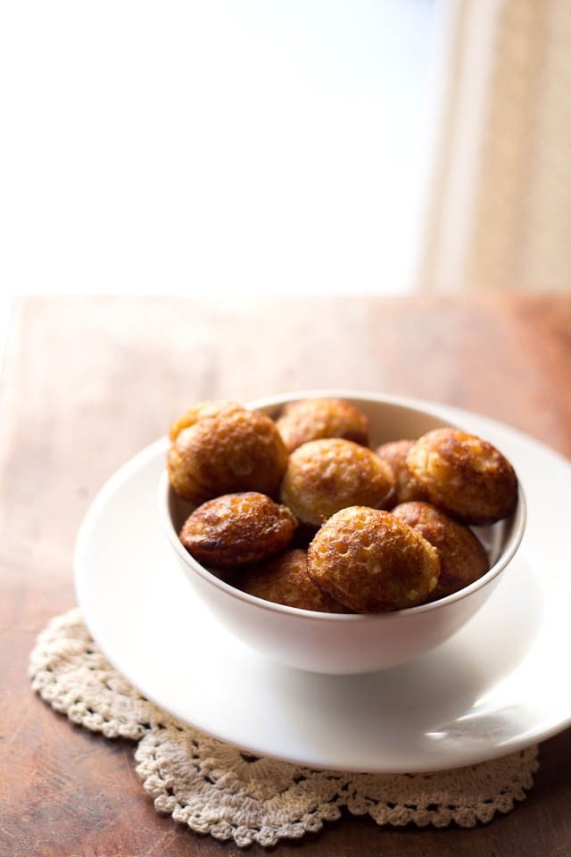 sweet paniyaram in a white bowl on a white plate.