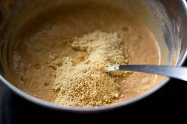 adding oil and roasted besan to hung curd mixture and mixing well