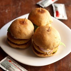 three aloo tikki burgers on a white plate.