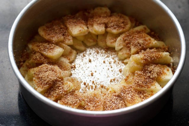 sprinkling cinnamon powder, nutmeg powder, demerara sugar and lemon juice on apple slices 