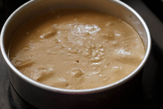 pouring cake batter in the prepared pan layered with apples