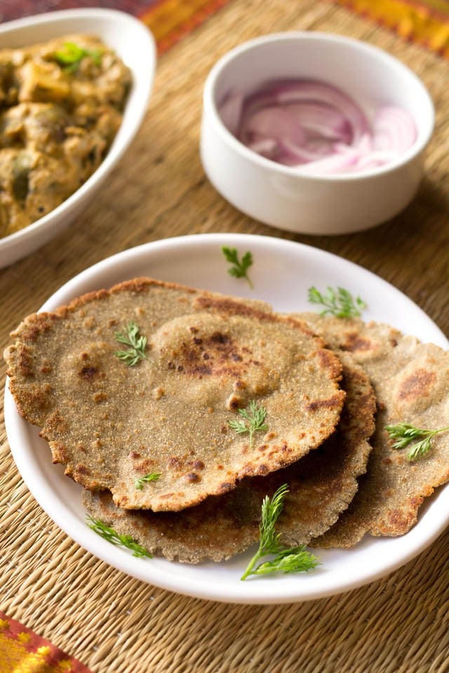 bajra bhakri (also known as bajra roti) on a round white plate garnished with coriander leaves.