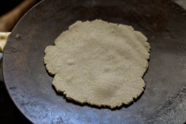 rolled bajre ki roti placed on hot, dry tawa.