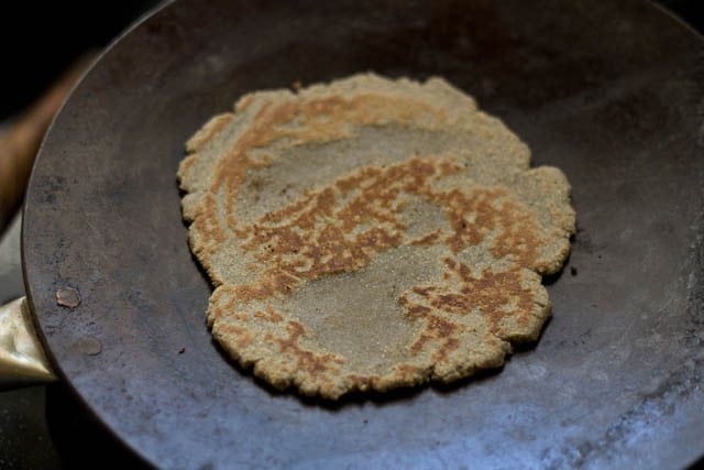 bajre ki roti is flecked with golden brown spots after being cooked on the tawa.