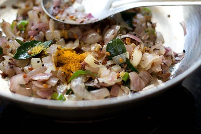 adding spices to pan for making puri bhaji.