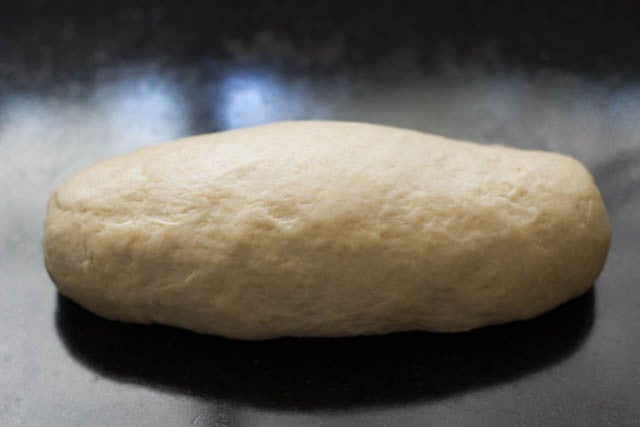 rolling brown bread dough into a log