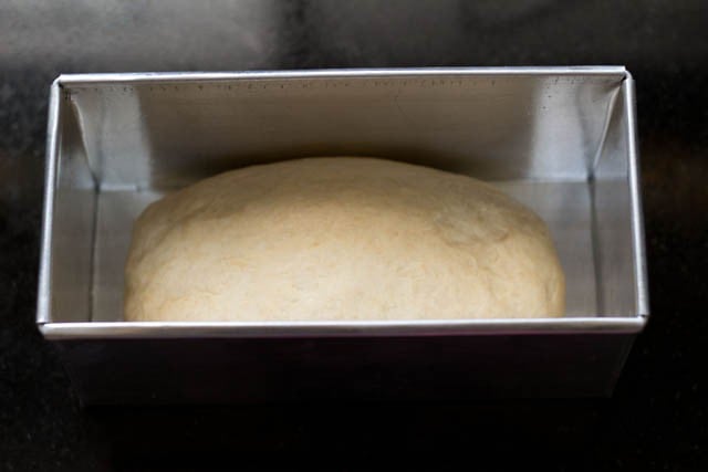 placing dough log in greased loaf pan with sealed edges down
