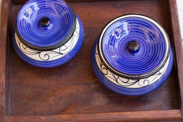 ceramic jars covered with lids on a wooden tray for the drink to ferment