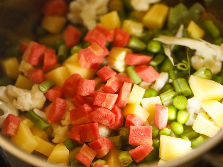 adding chopped vegetables like carrots, green beans, cauliflower, baby corn etc