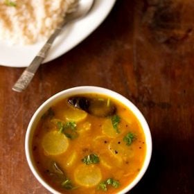 radish sambar served in a bowl with a plate of steamed rice with a spoon kept in the background.