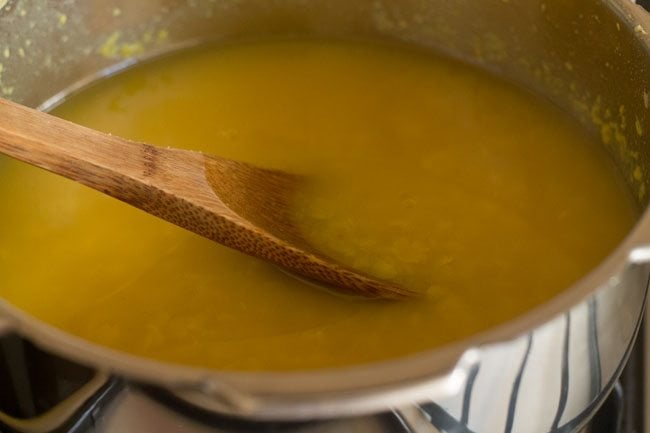 mashing cooked lentils with a spoon