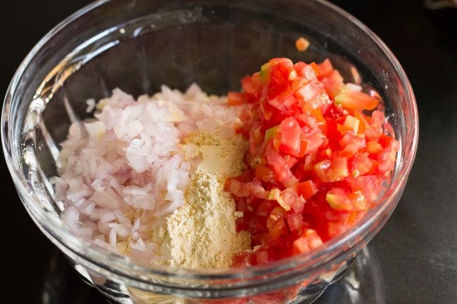 gram flour, onions and tomatoes in glass mixing bowl