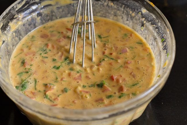 tomato omelette batter in bowl with a whisk inside