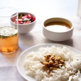 chawli usal served over a bed of rice on white plate.