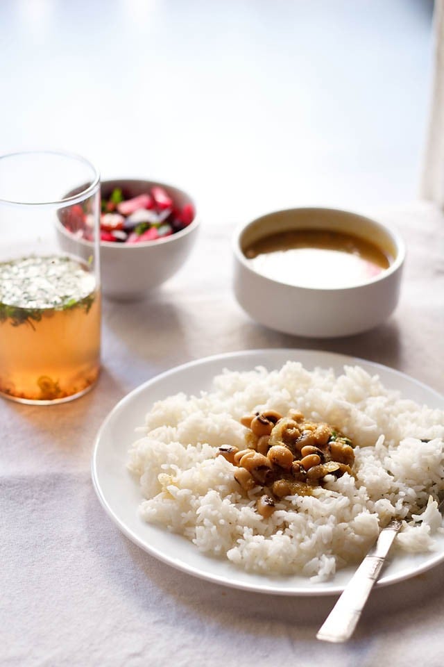 chawli usal served over a bed of rice on white plate.