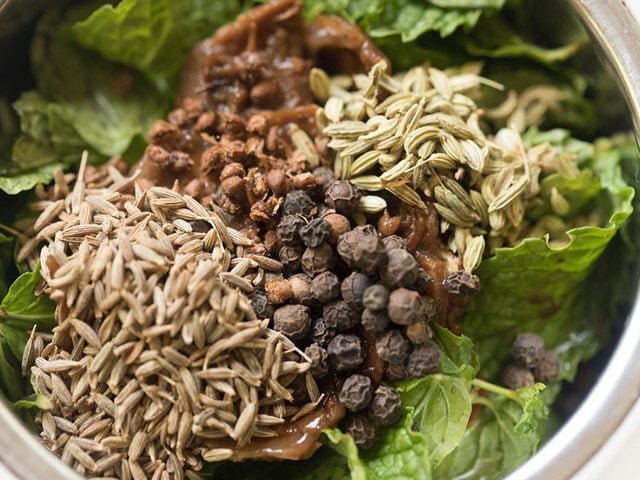 adding spices to mint leaves and tamarind in grinder jar