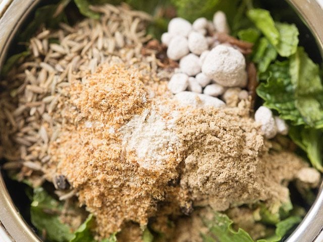 adding dried mango powder, chaat masala, asafoetida and black salt in the grinder jar 