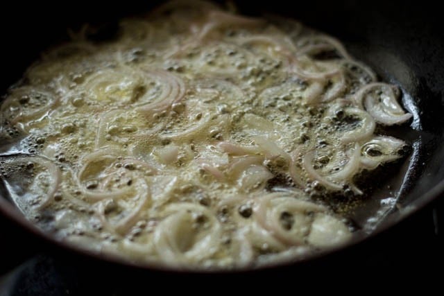 frying half the sliced onions in hot oil for kerala biryani