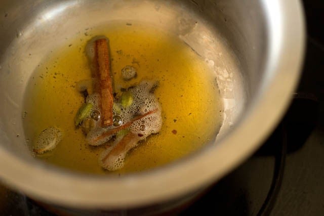 frying cinnamon, cloves and green cardamoms in hot oil for kerala biryani 