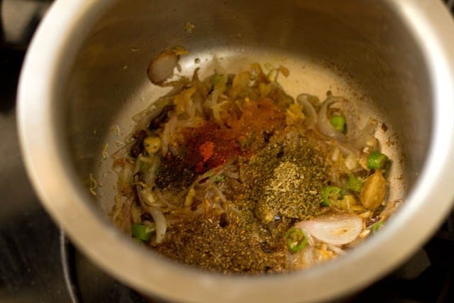 frying spice powders with sliced onions and whole spices for kerala biryani 