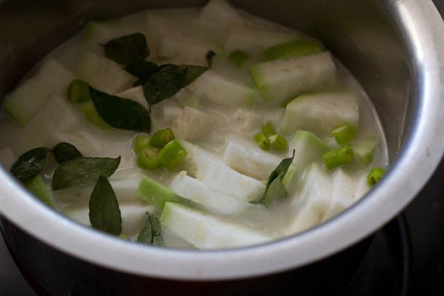 mixing chopped lauki or bottle gourd, salt,, yogurt, curry leaves, chopped green chilies and water in a pan