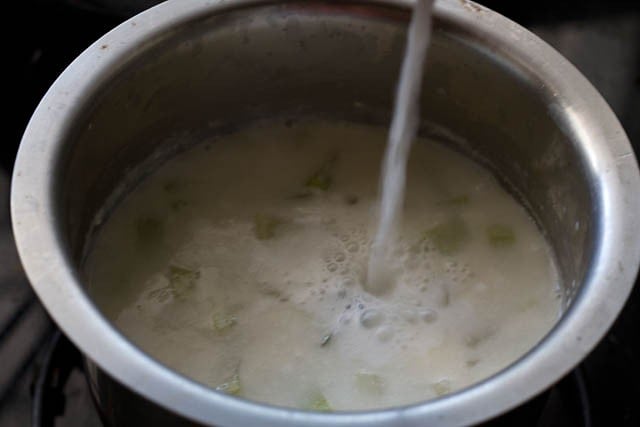 adding coconut milk to lauki curry in pan