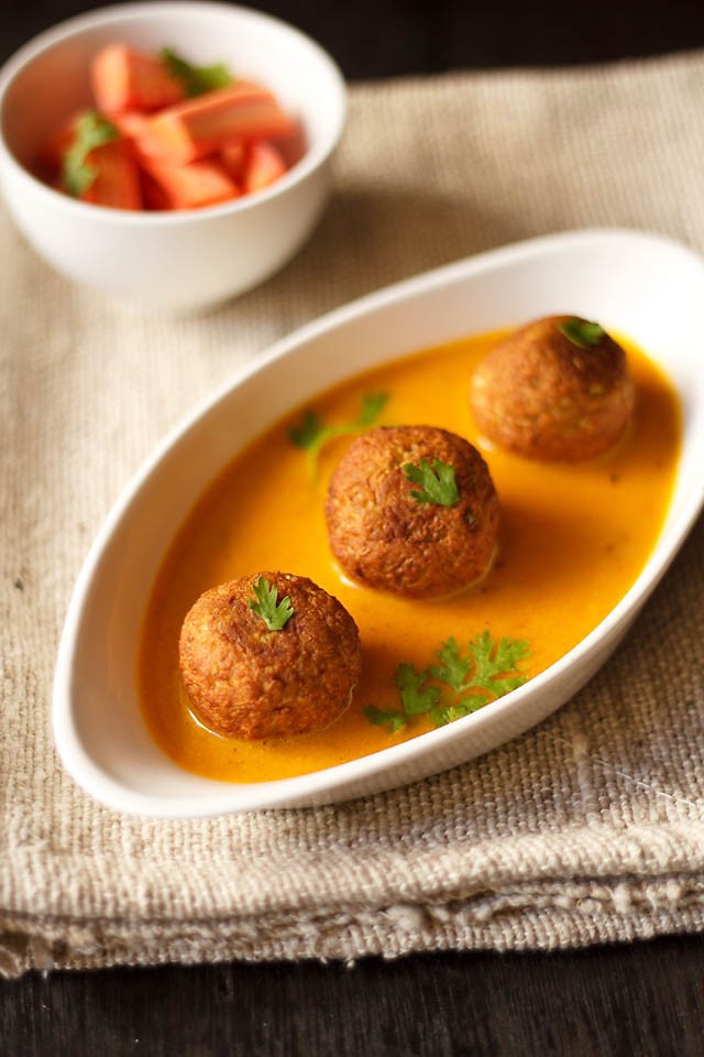 lauki ke kofte served in a serving bowl with carrot batons in a bowl.