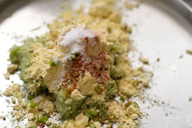 adding gram flour, garam masala powder, red chili powder, chopped green chili and salt to grated lauki.