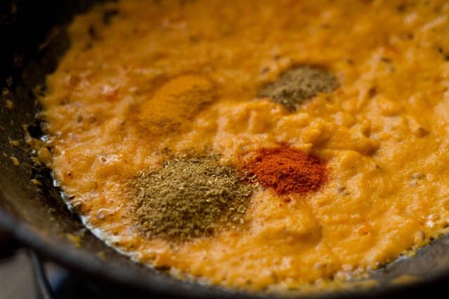 adding turmeric powder, red chili powder, coriander powder and garam masala powder to thickened masala paste.