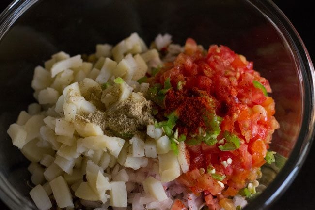 red chili powder and chaat masala on top of chopped tomatoes and chopped boiled potatoes