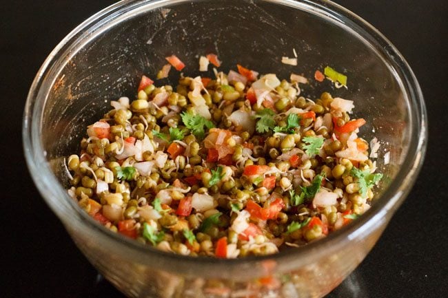 garnishing sprouted moong salad in bowl with chopped coriander leaves 