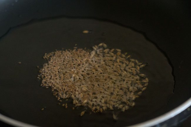 carom seeds and cumin seeds added to hot oil in pan. 