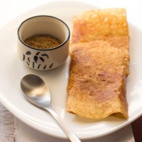 pav bhaji dosa with idli podi in a small bowl on a white plate with a small spoon.