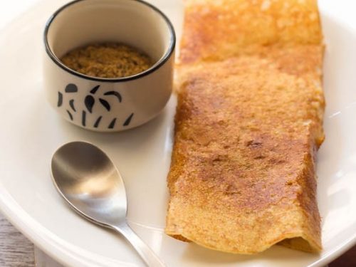 pav bhaji dosa with idli podi in a small bowl on a white plate with a small spoon.