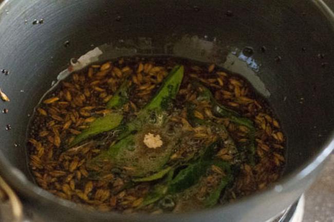 adding asafoetida and curry leaves in hot oil for tempering