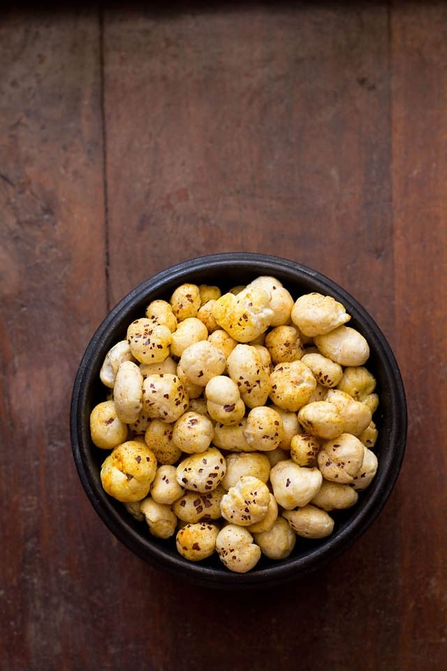 roasted makhana recipe or phool makhana in a black bowl on a dark wooden table. 