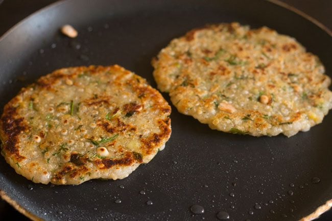 cooking 2 sabudana thalipeeth on frying pan