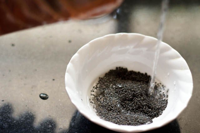 adding water to sabja seeds in bowl.