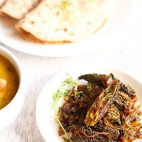 bharwa karela served on a white plate with roti.